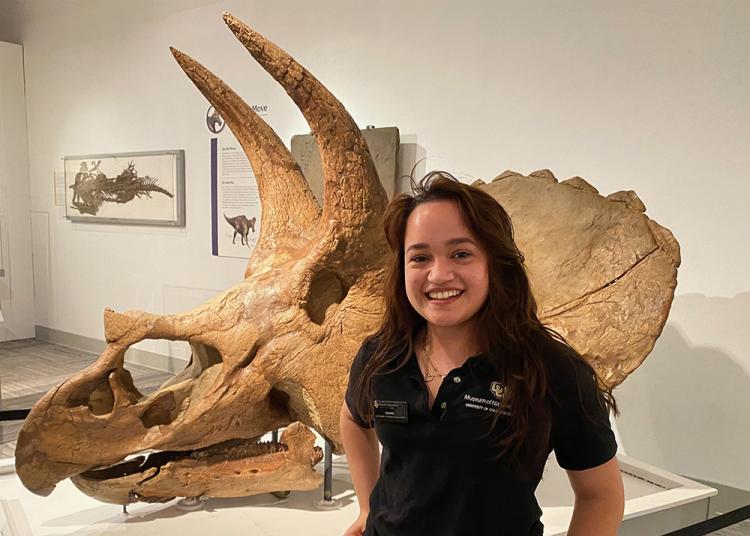 Ayesha standing in front of triceratops skull in the paleontology hall