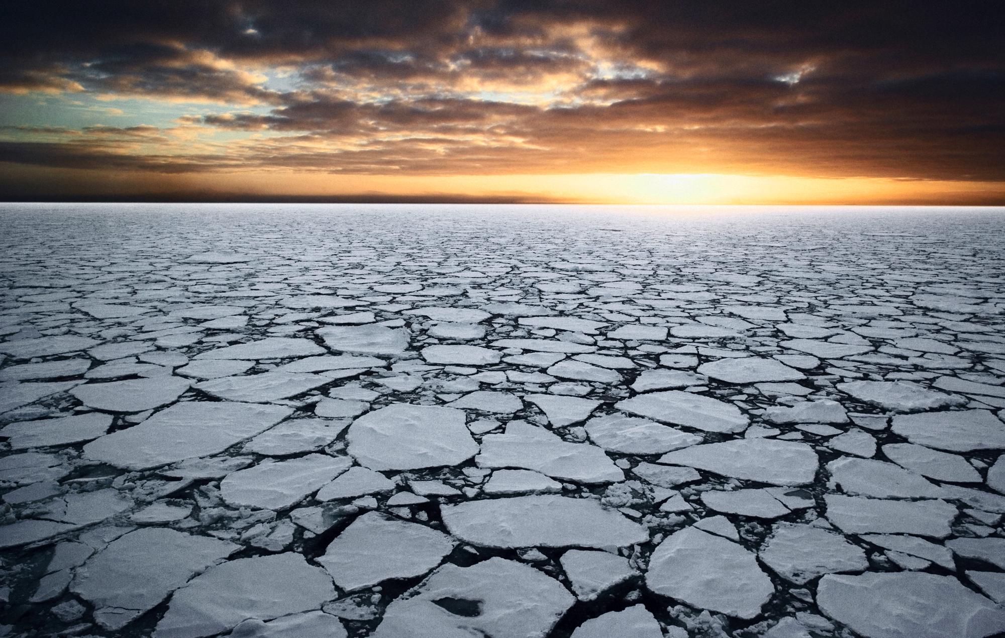 Sea ice broken into small pieces with sunrise in the background.