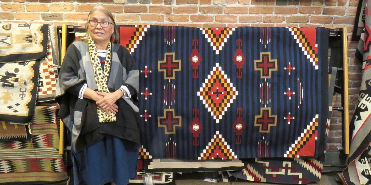 Woman standing next to rug with geometric patterns