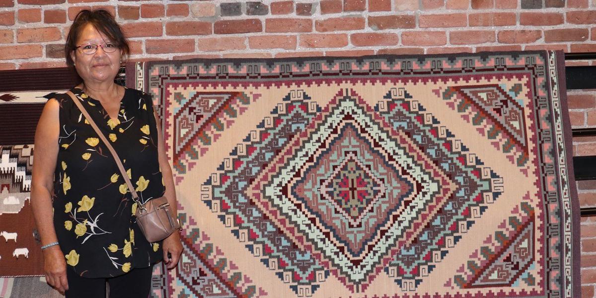 woman standing next to rug with geometric designs