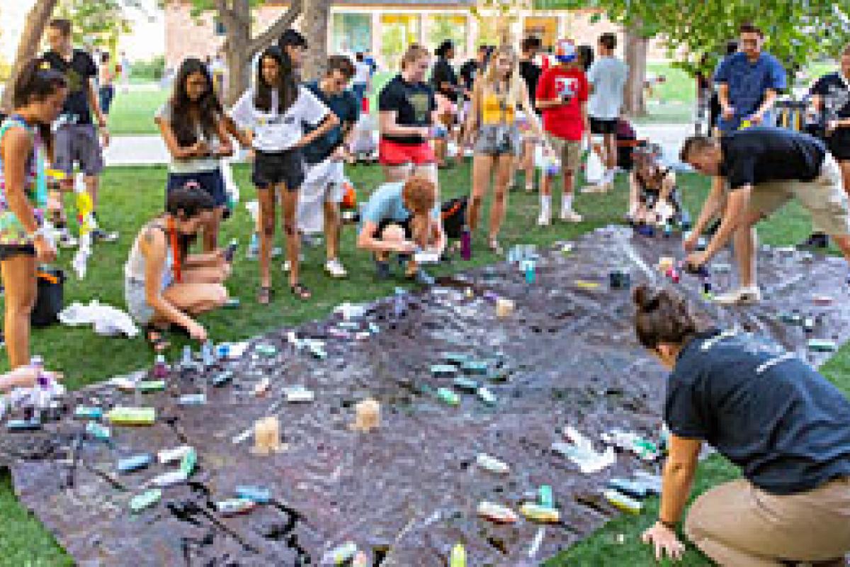 students painting on plastic sheet outside