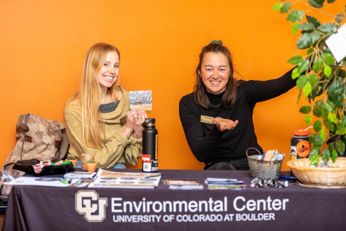 students sitting at a table holding a postcard with a picture of an elk