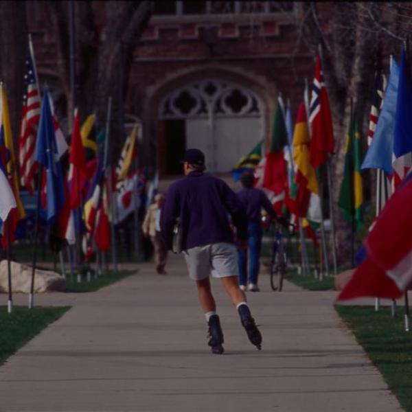 A rollerblader cruises through the CWA flags on the CU Boulder campus