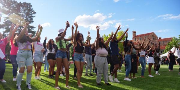 a large group of students dancing together on a field during CUnity Fest 