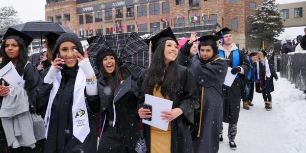 students during CU Boulder's May 2019 commencement, wearing grad regalia in the snow