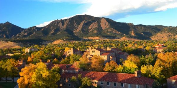 a view of campus with fall foliage and the flatirons in the background
