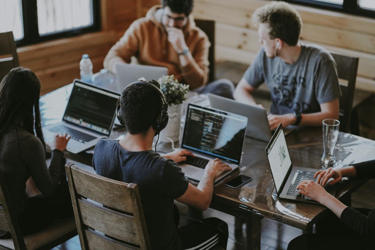 Students sitting around a table working on laptop computers