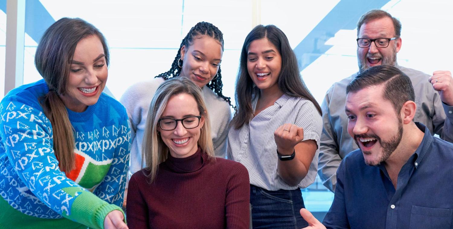 A group of smiling people looking at a computer.