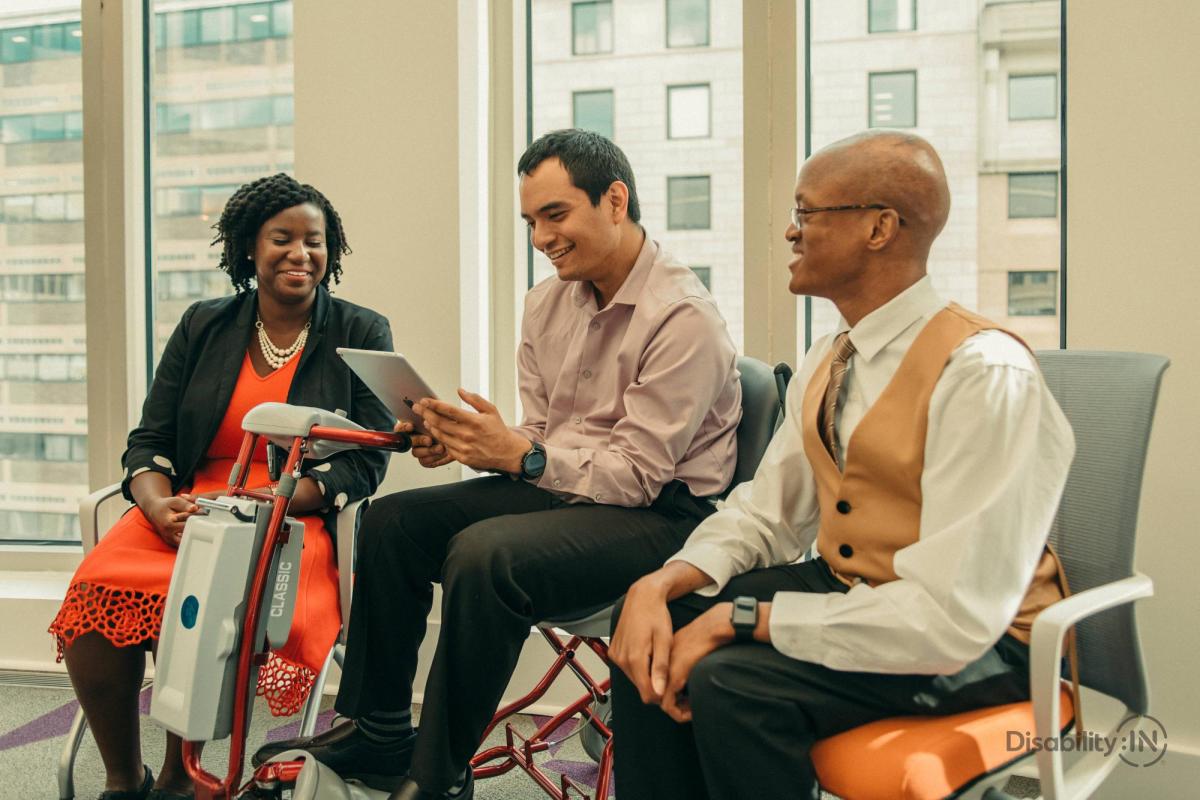 Three people with disabilities looking over an iPad.