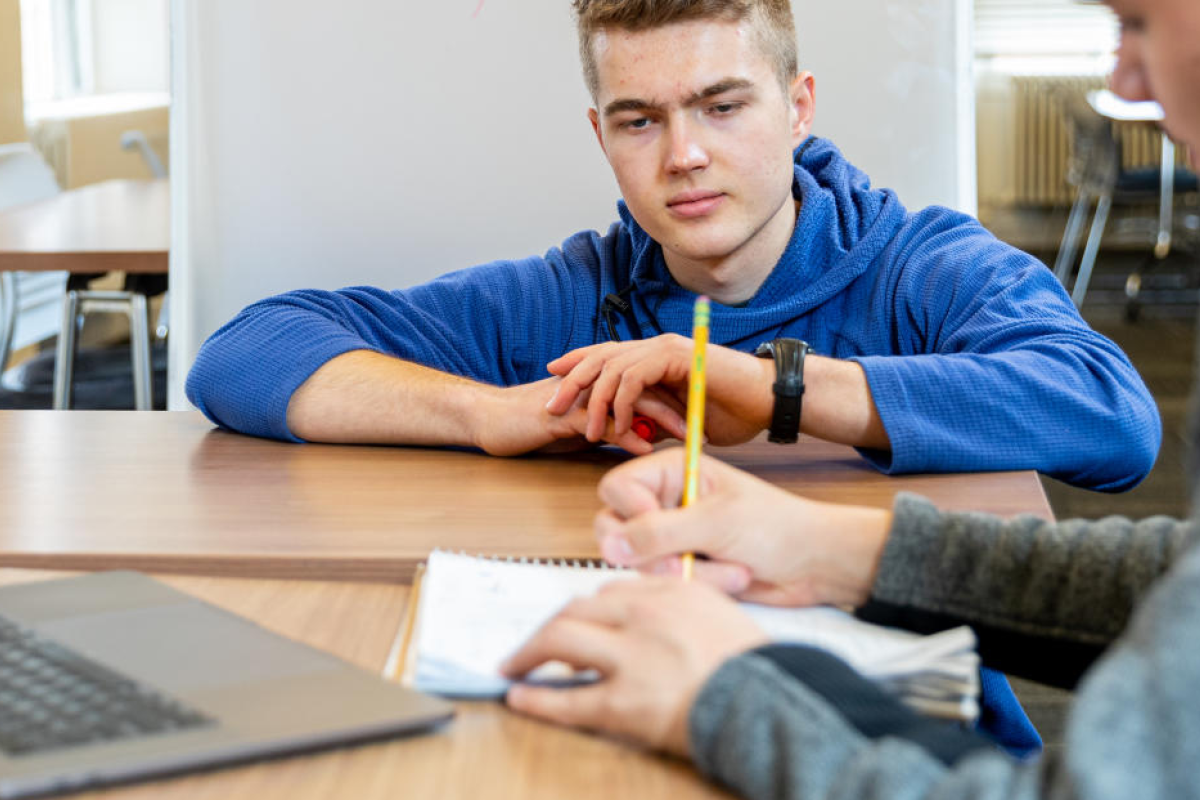 student helping another student with homework at a desk