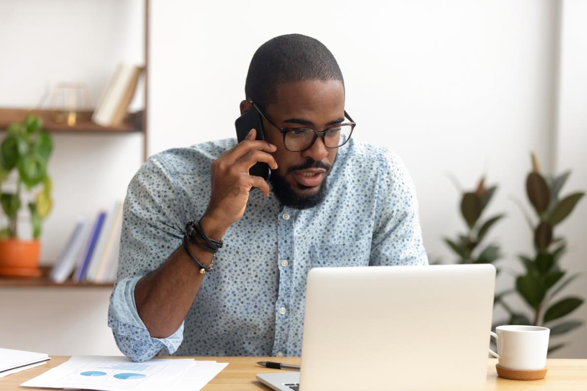 man working on phone and computer
