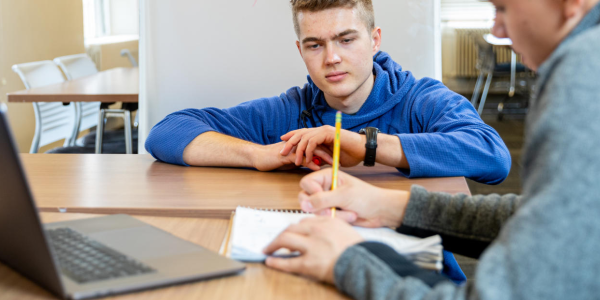 student helping another student with homework at a desk