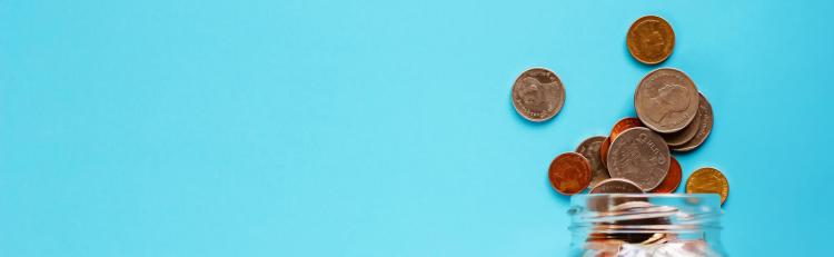 Photo of a jar of coins spilling out on a table.