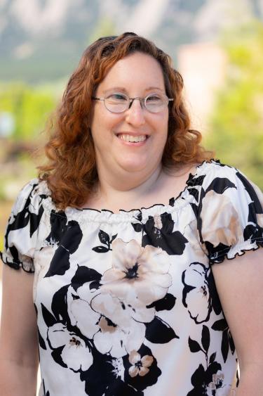 smiling woman with red hair and round glasses