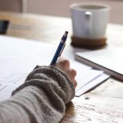 person working on a desk with a pen and paper