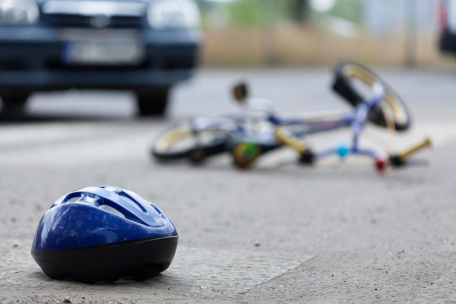 Bike and bike helmet in middle of the street, car in background
