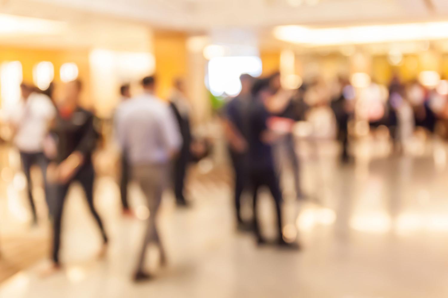 Blurry crowd of people standing and walking indoors