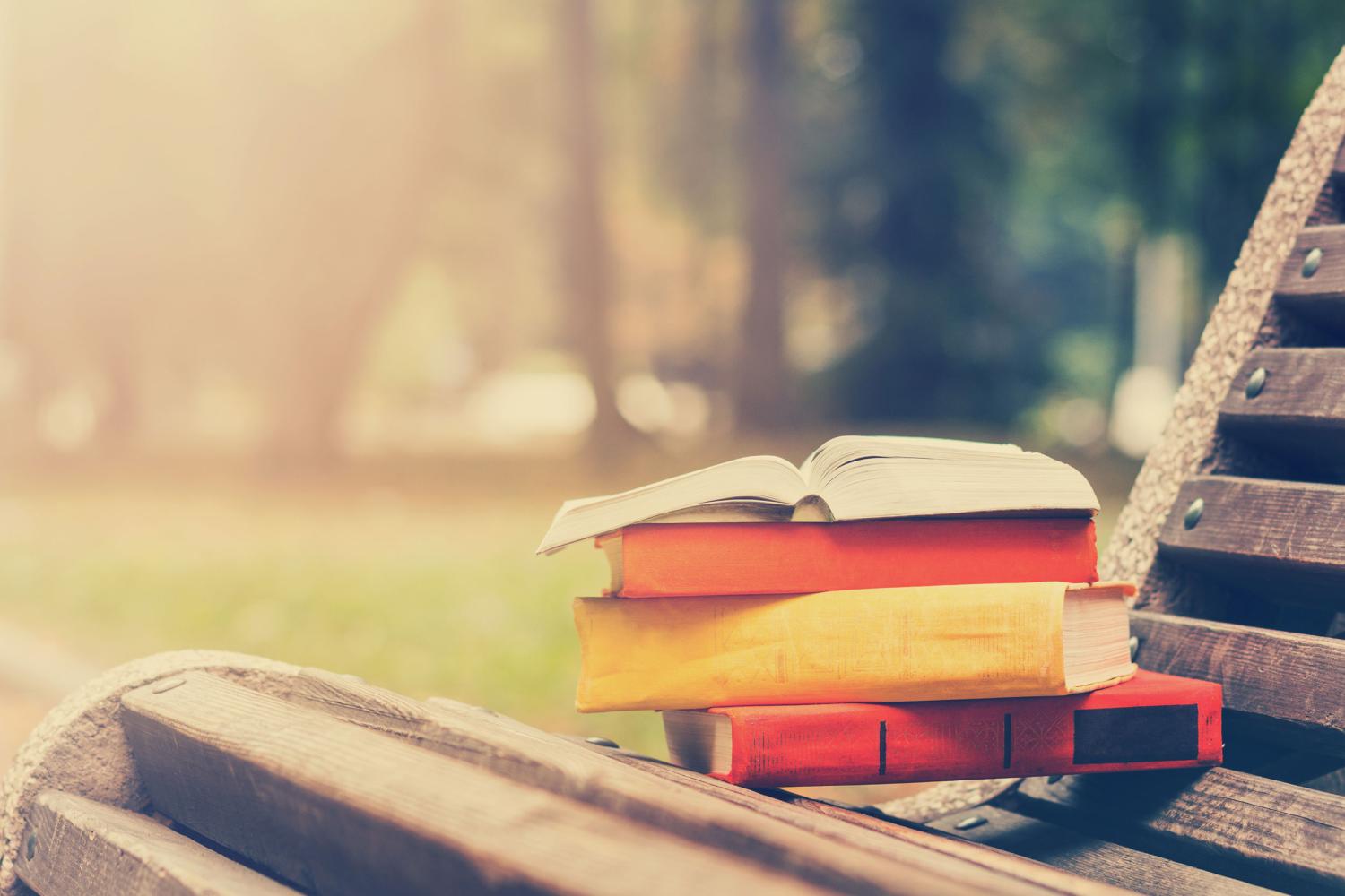 Books staked on a bench outdoors