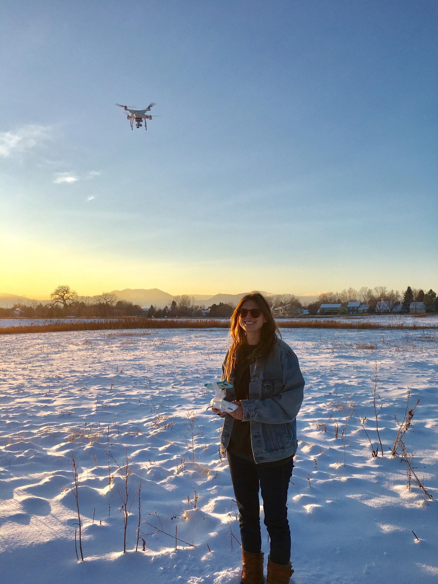 Coohill pilots a drone over a snowy field.