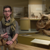 student discusses methods of sucess in front of large dinosaur skull 