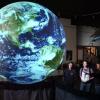 students stand behind a projection of the globe