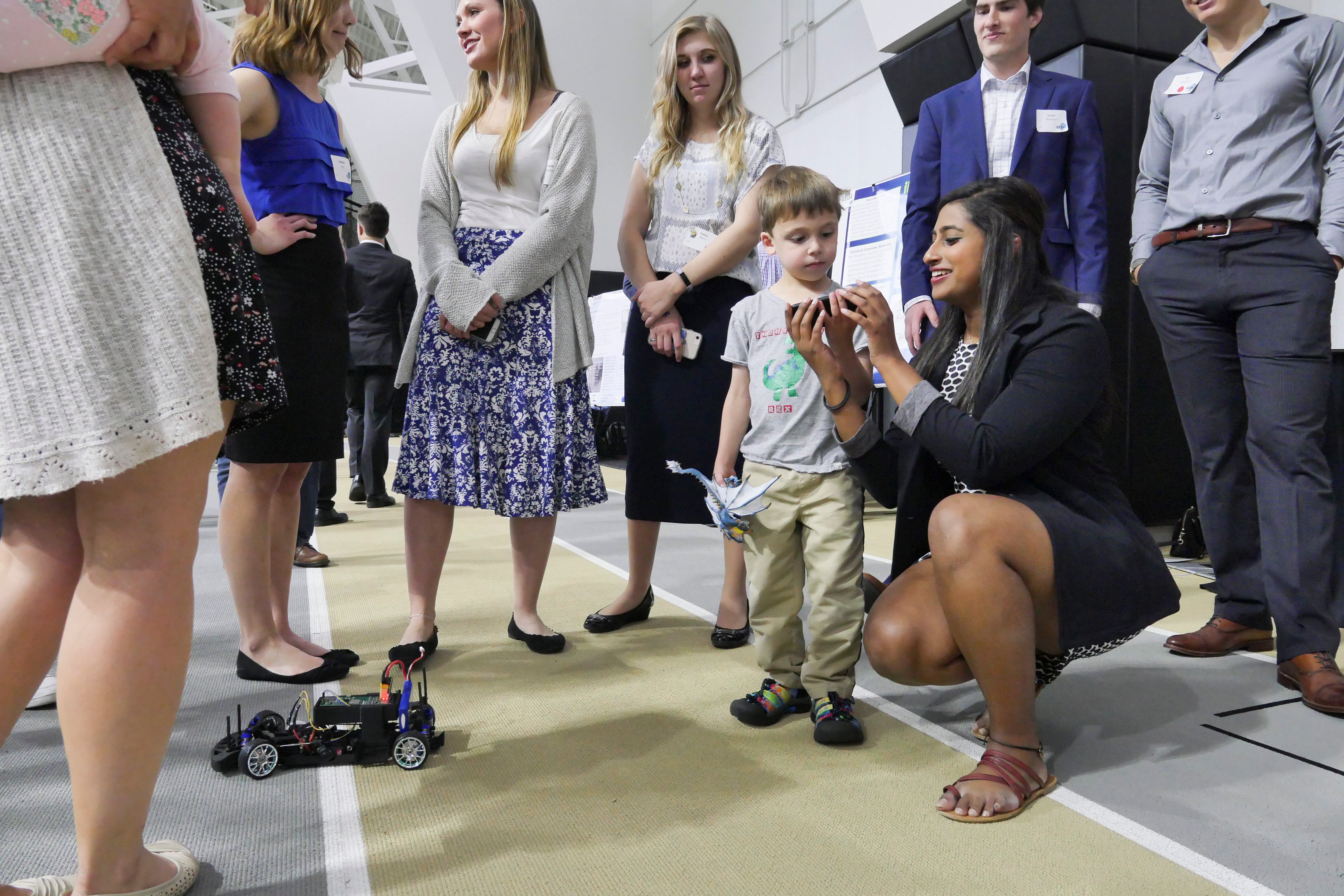 A student shows off her robotic car project to a young attendee at the 2019 Engineering Projects Expo