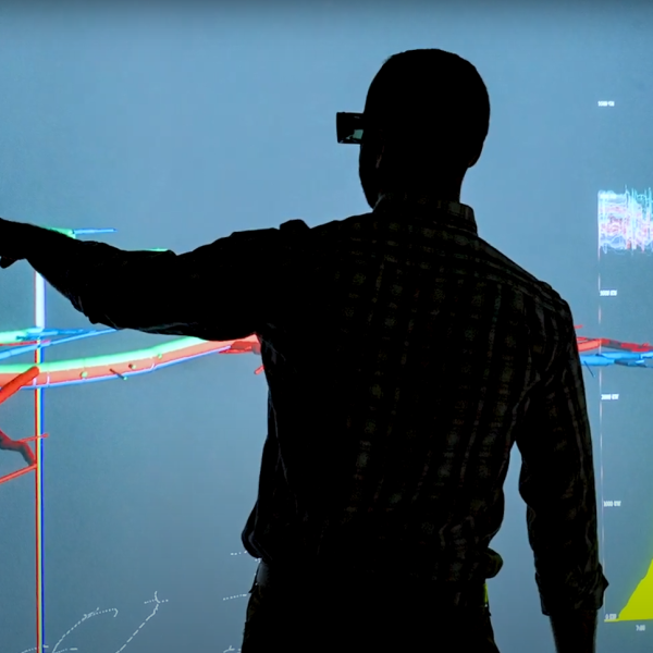 Silhouettes of Hodge and a colleague discussing data on a wall-sized screen at NREL