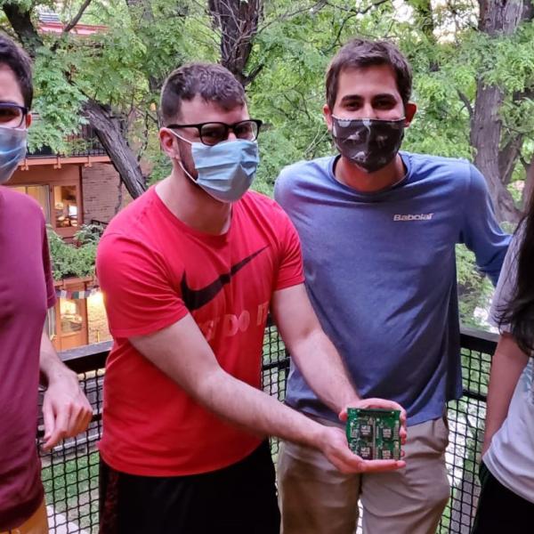 Four masked team members show off their prototype during a testing session at a team member's home.