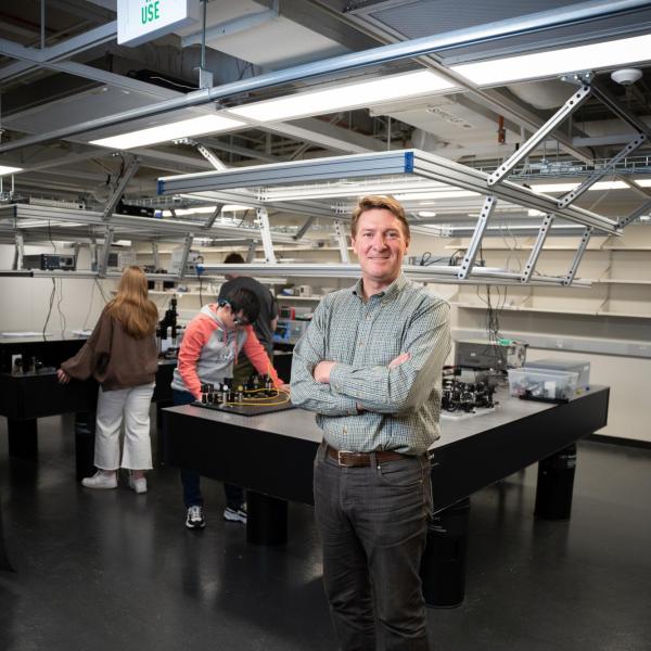 Diddams in front of optical tables where students are at work on projects