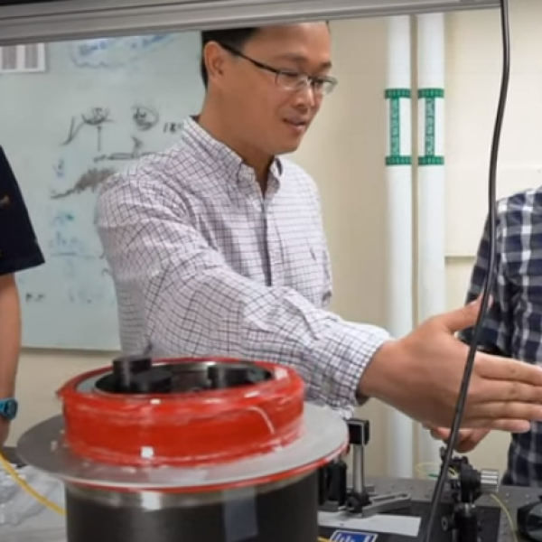 Huang and a grad student discuss a project at an optical table in their lab