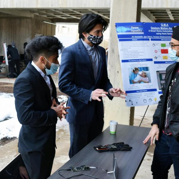 Members of the Squad Es team demonstrate their gesture motion assistant device for expo visitors.