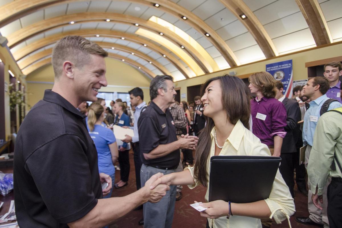 A student meets an employer at a campus career fair.