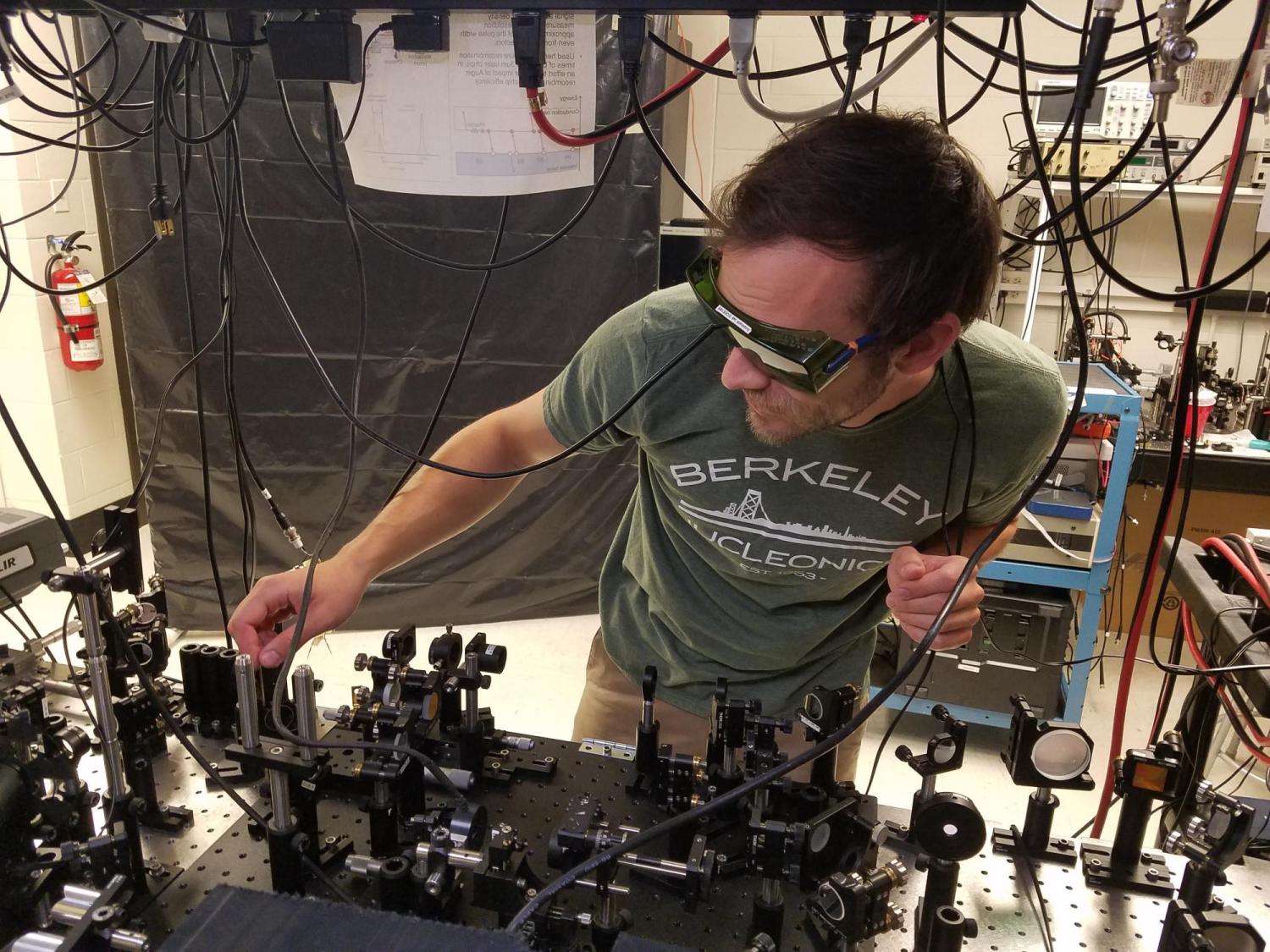 Brendan Heffernan adjusts optical components at a light table in the team's lab.