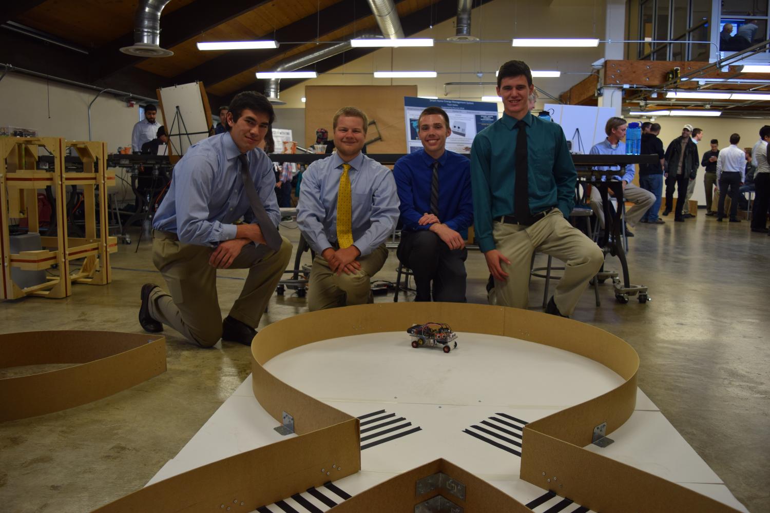 The four members of Ohm Wreckers kneel behind their figure-eight track at the 2016 capstone expo.