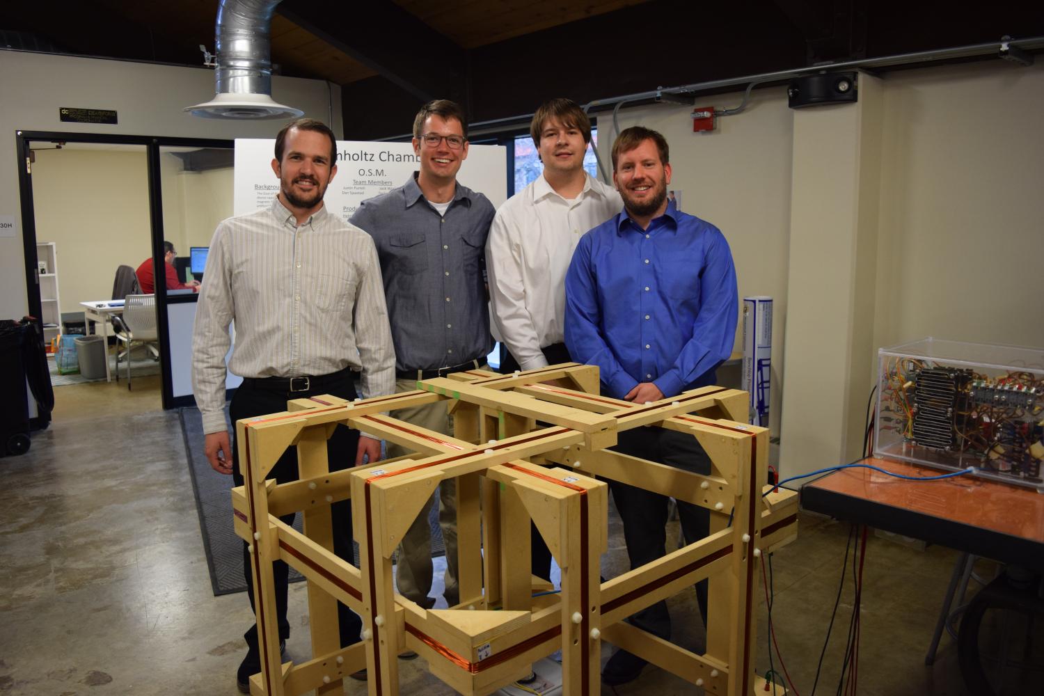 The four members of Orbital Space Magnetics gather around their Helmholtz chamber prototype at the senior capstone expo.