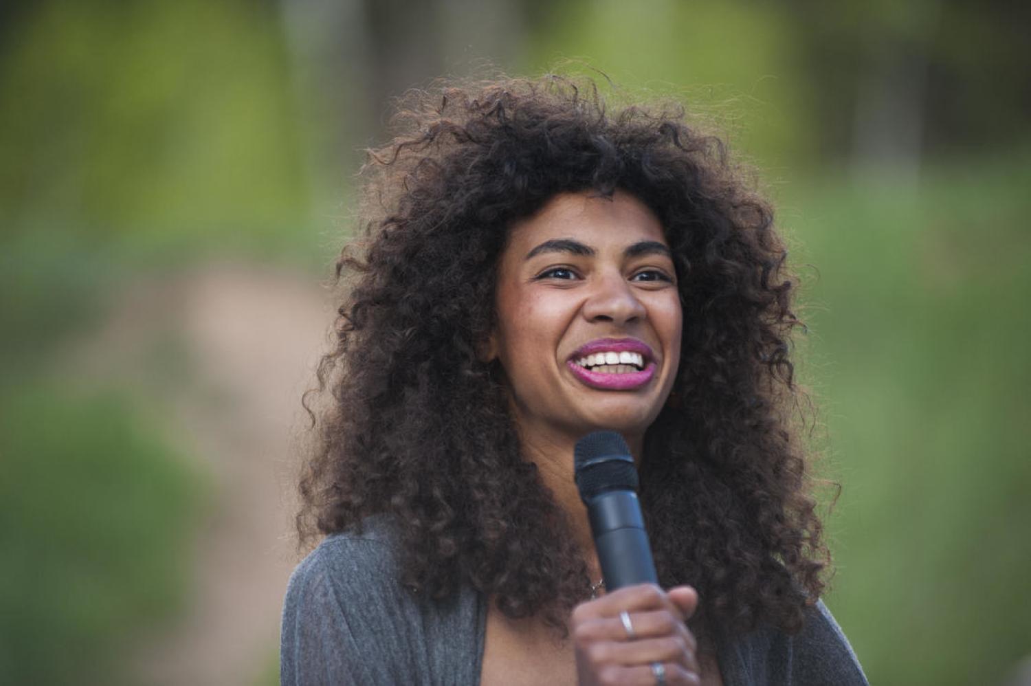 Krueger with a microphone, smiling as she speaks to an audience