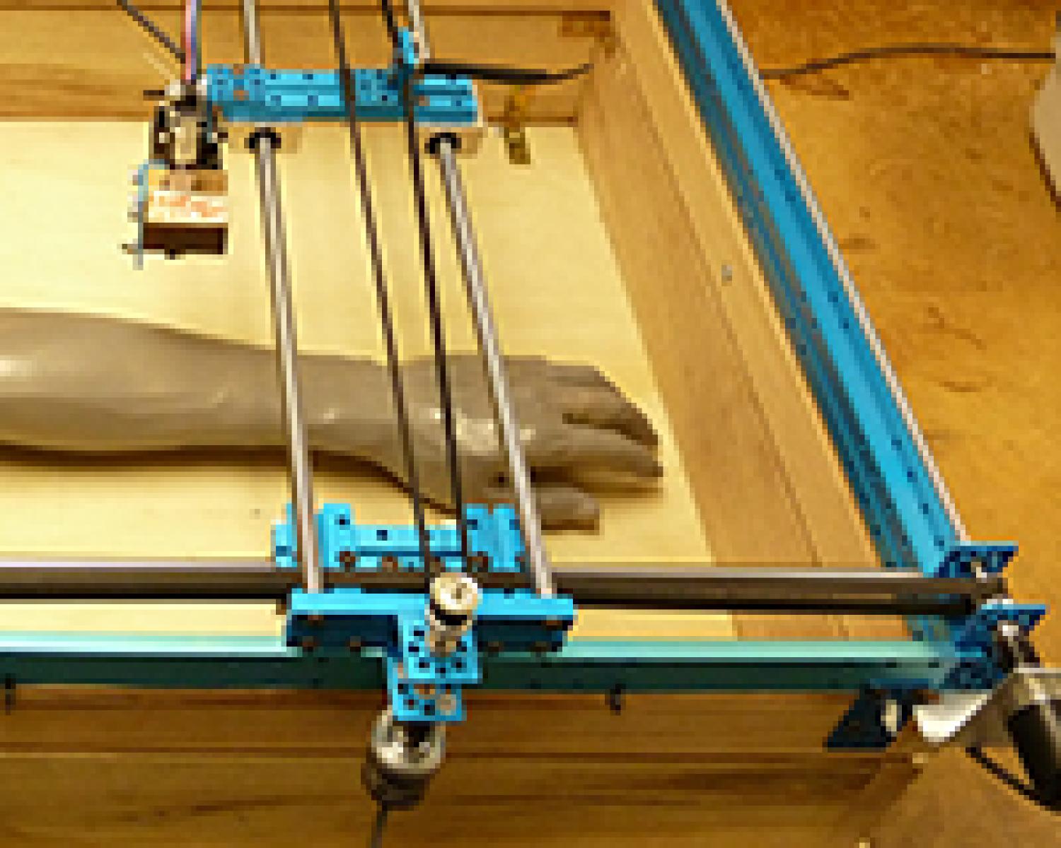 A simulated tattooed arm sits inside the SKINlapZ robot workspace