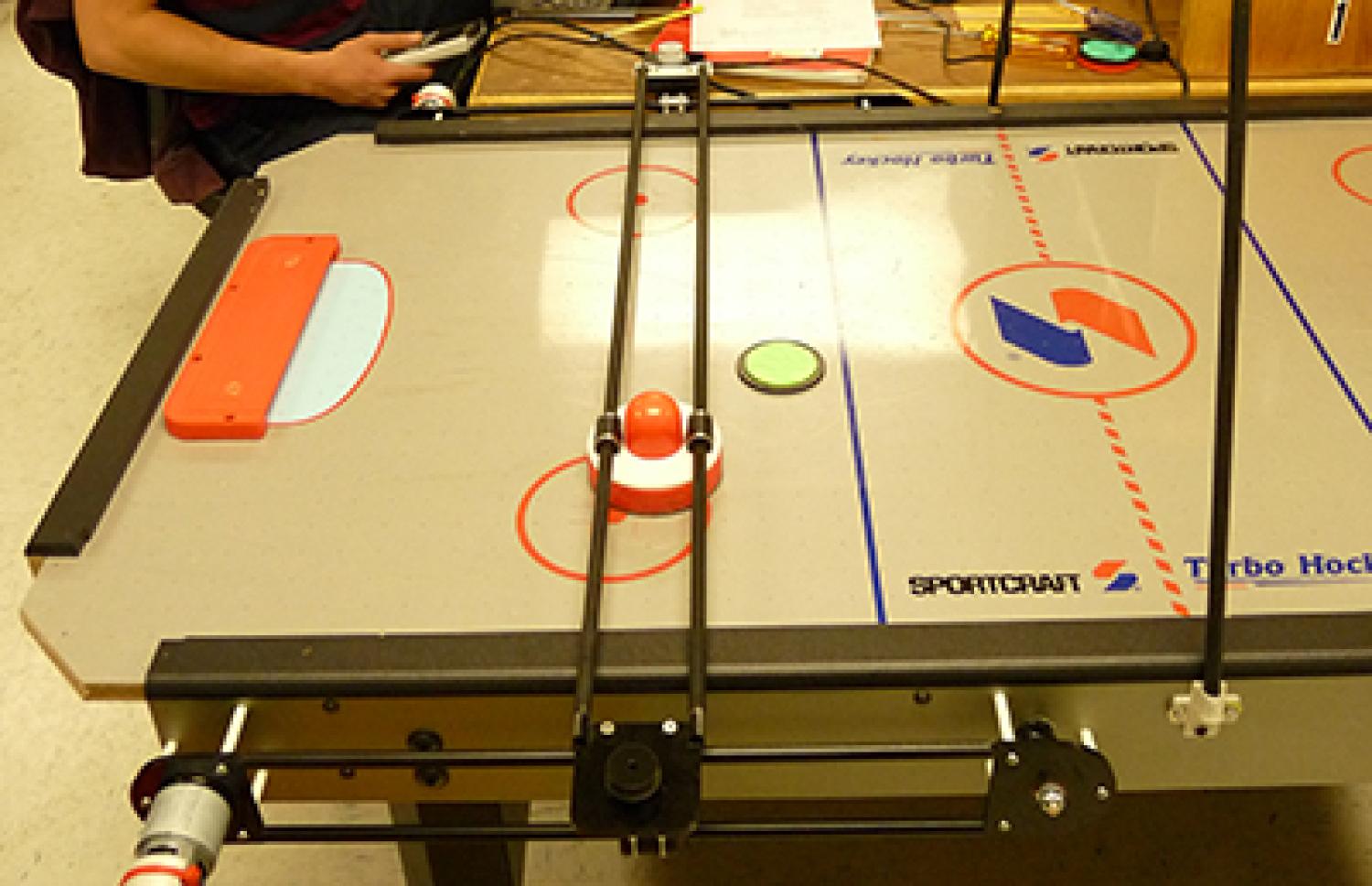 A puck rests on an air hockey table that is being modified to be autonomous