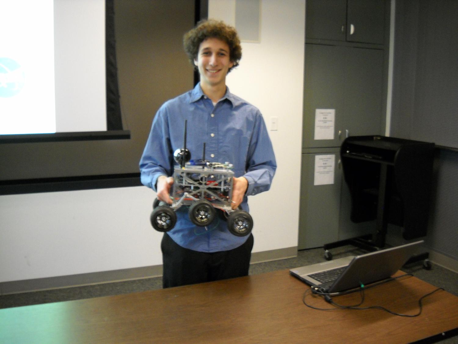 Philip Maksimovic holds a prototype of his multi-rover system