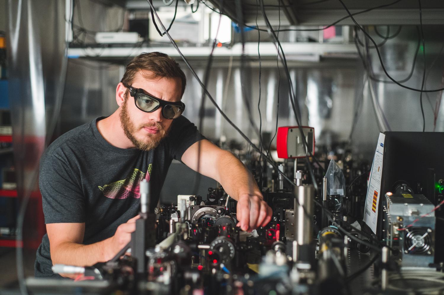 A student works at an optics table in a lab.