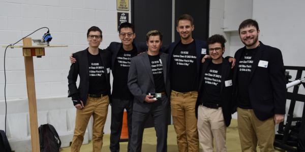 The team in matching capstone T-shirts and suit jackets at the Engineering Projects Expo