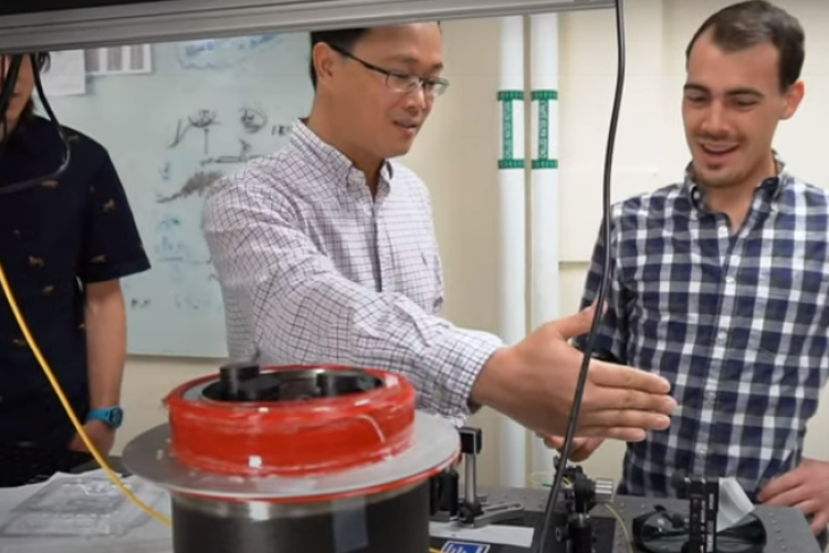 Huang and a grad student discuss a project at an optical table in their lab