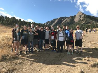 The class poses for a group photo with the Flatirons in the background