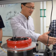 Huang and a grad student discuss a project at an optical table in their lab