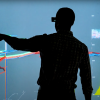 Silhouettes of Hodge and a colleague discussing data on a wall-sized screen at NREL