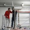 Misha Sinner and a fellow student stand on scaffolding to work on a turbine model.