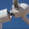 Workers guide the rotor and blades onto the tower during assembly of the turbine. 