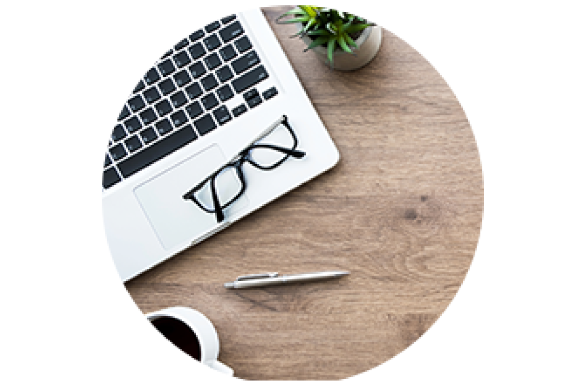 A laptop on a desk with a cup of coffee, a pen and a plant