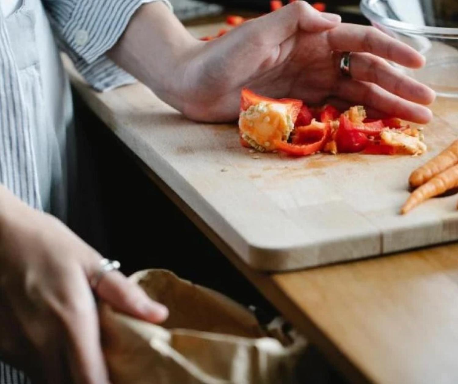 woman cleaning food scraps off a cutting board