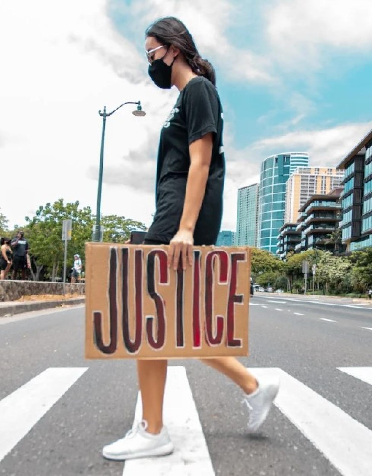 girl crossing street with justice sign